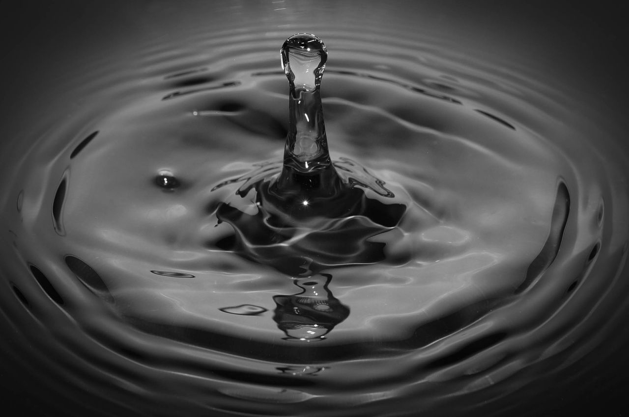 The Art of Drawing Readers In: Your attractive post title goes here Artistic black and white macro photo of a water droplet splash with ripple effects.