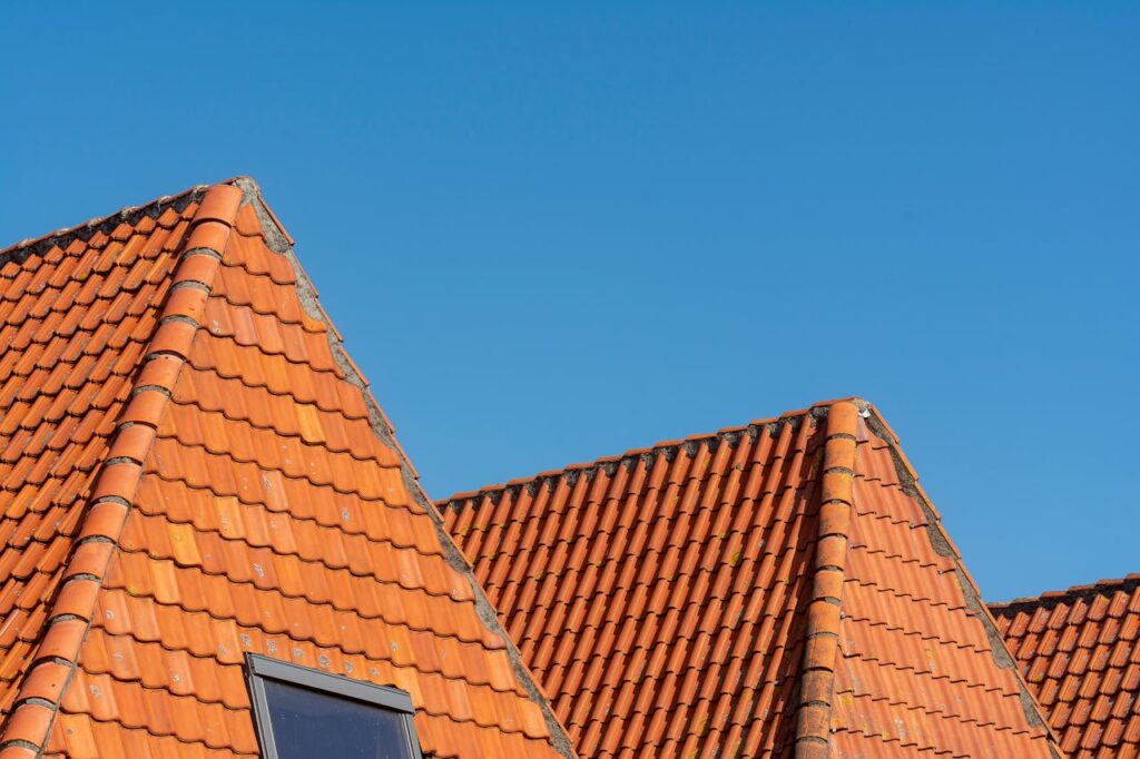 pexels photo 29114658 Close-up of red tiled roofs under a clear blue sky, showcasing architectural design.